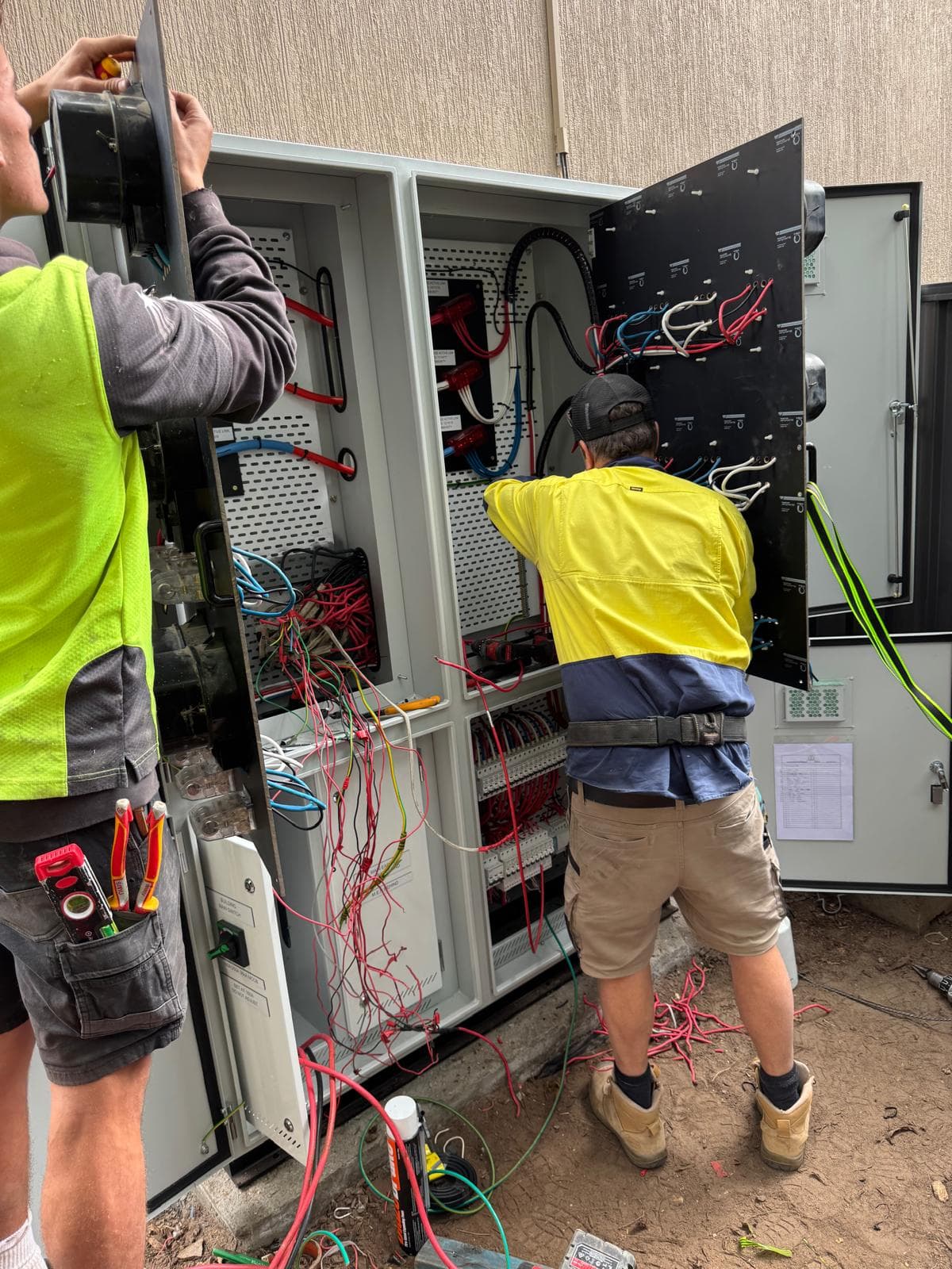 Two RME electricians working inside an open switchboard